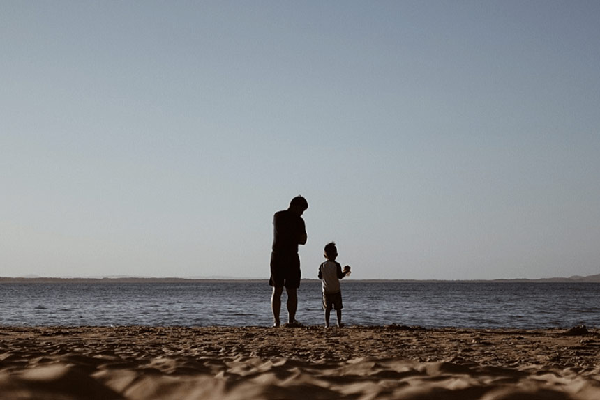 A man and his son standing on the beach