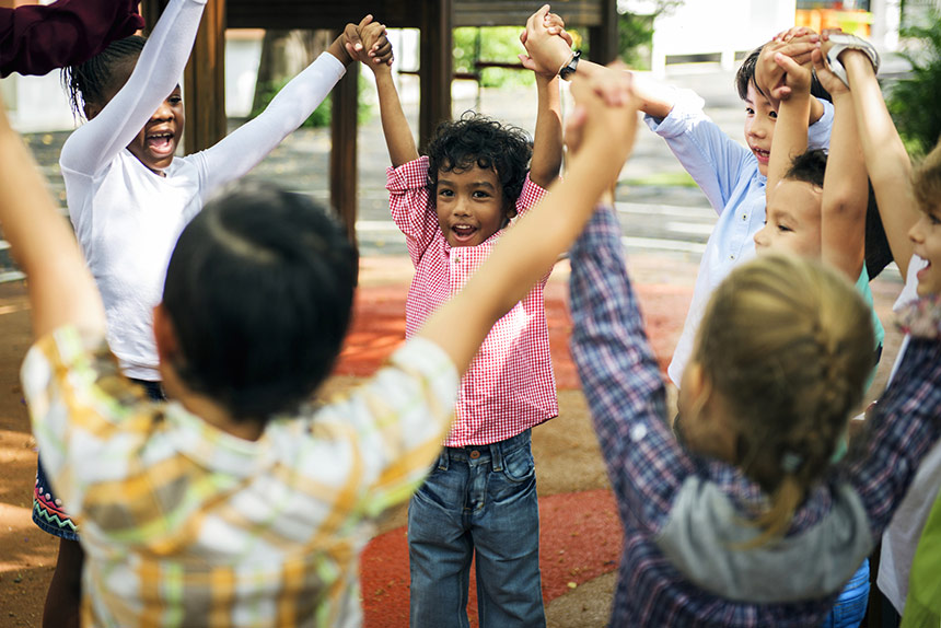 Children in a circle with arms upraised and holding hands
