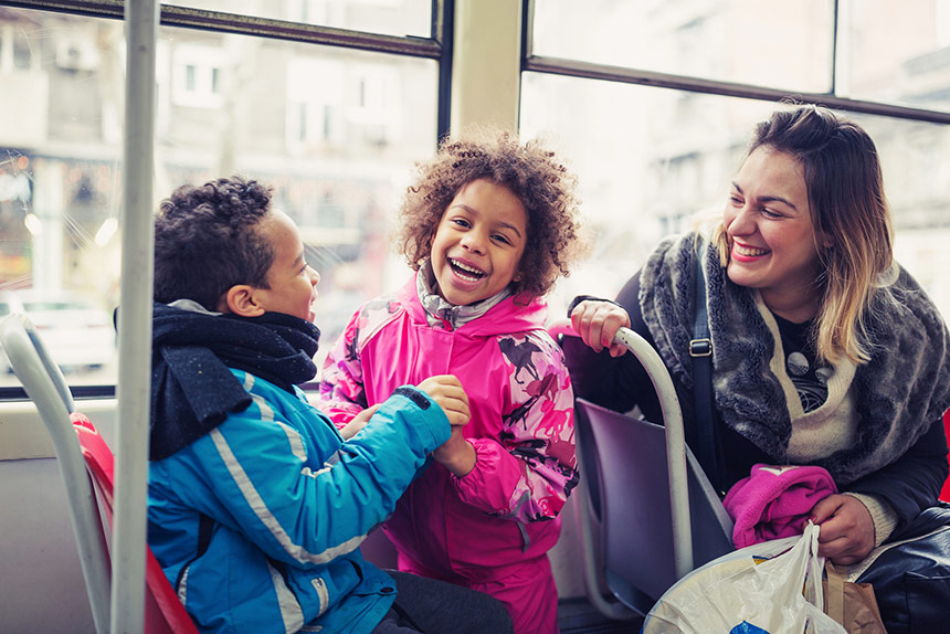 Laughing children on a bus with smiling adult