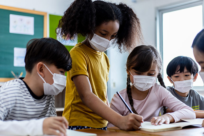 Diverse group of children in a classroom wearing masks