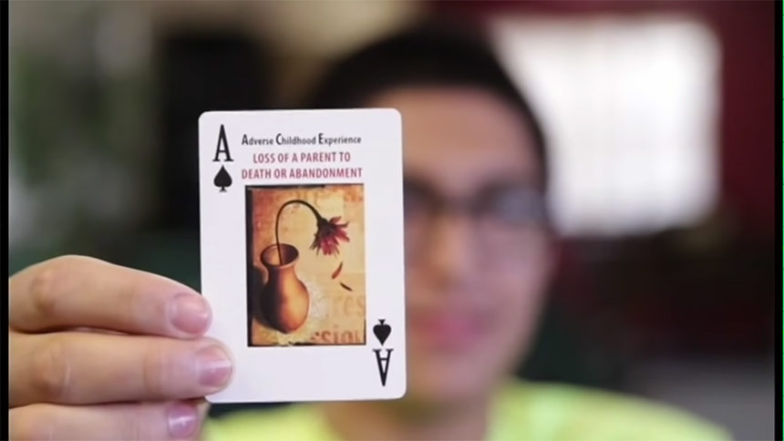 Video still of a young man holding up an ace of spades