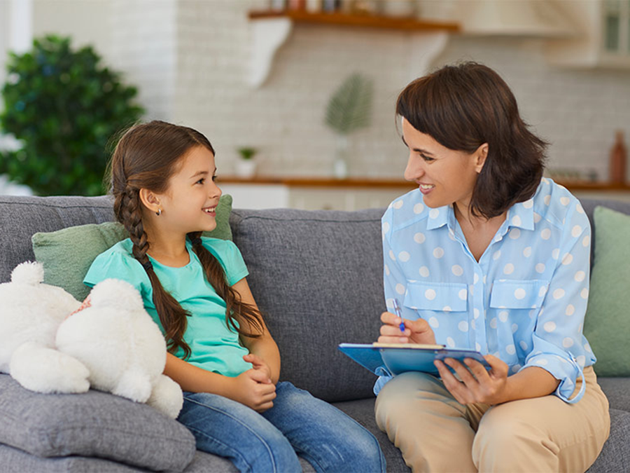 Photo of a woman holding a clipboard sitting on a couch with a little girl