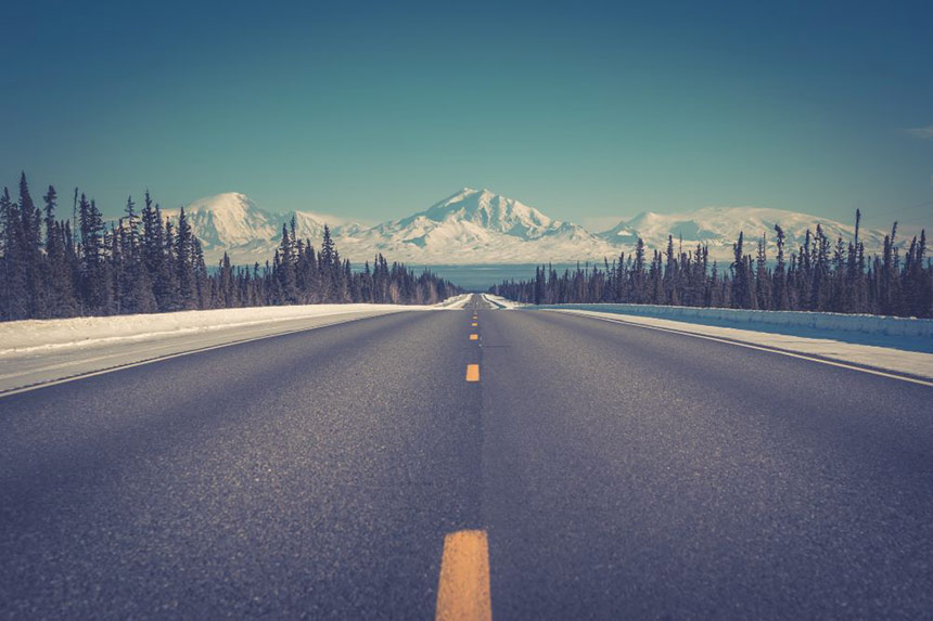 Photo of a road with snowy mountains in the background