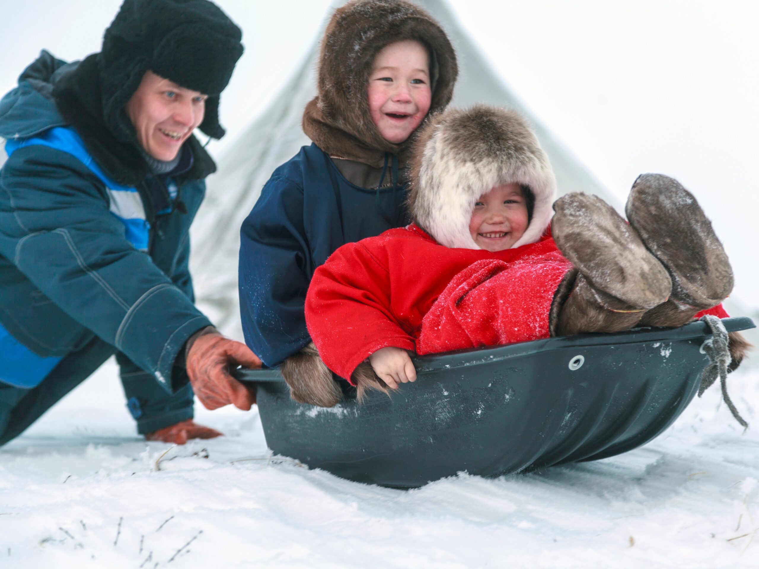 Father and children sliding in the snow.