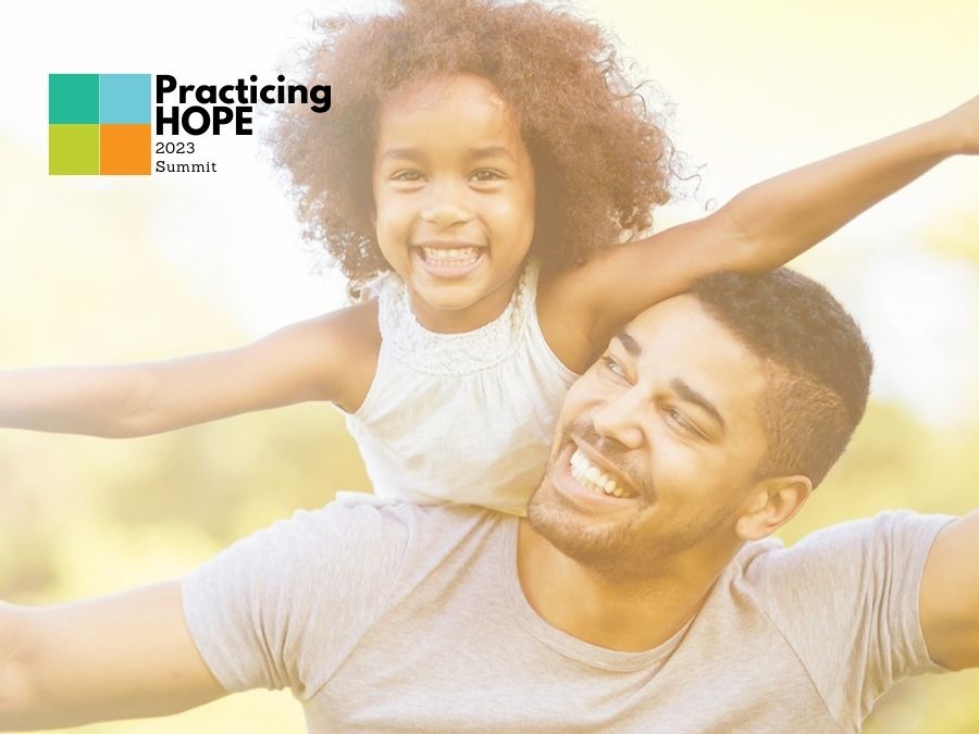 Child on Fathers shoulders smiling.