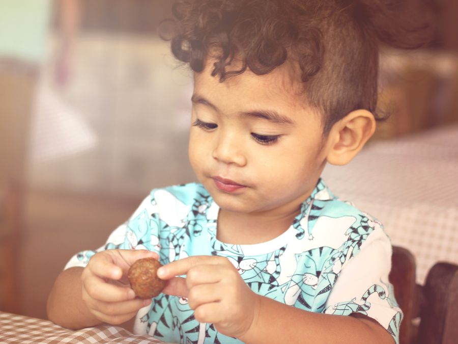 Baby eating a meatball.