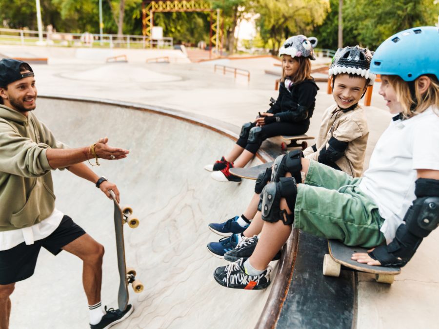 Adult teaching children how to skateboard.