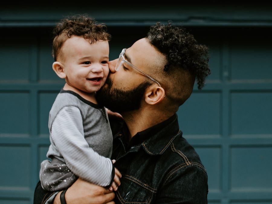 Man carrying baby boy and kissing on cheek
