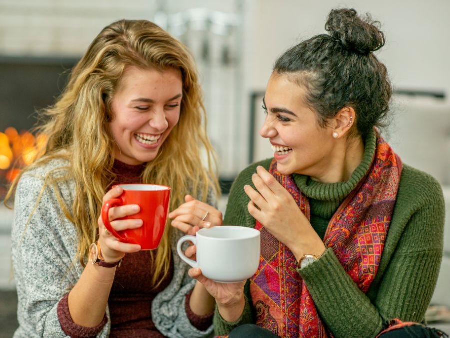 Two friends drinking coffee and laughing.
