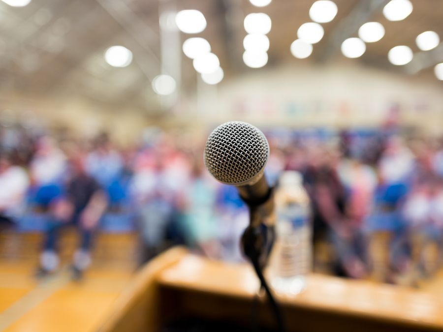 Microphone on a podium with blurry crowd in background.