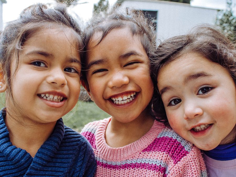 Three children smiling at together.