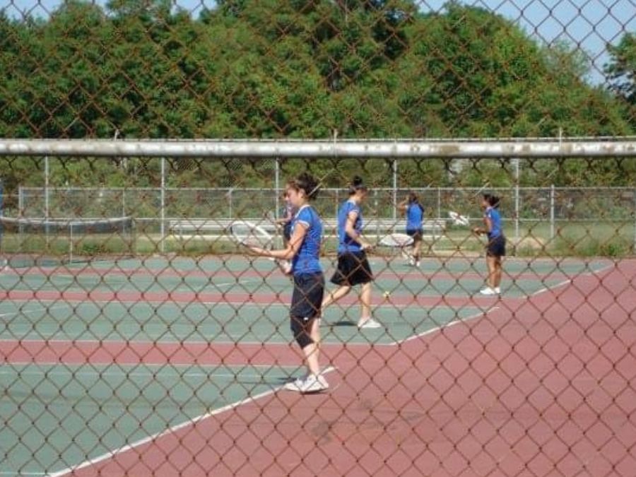 High school youth playing tennis.