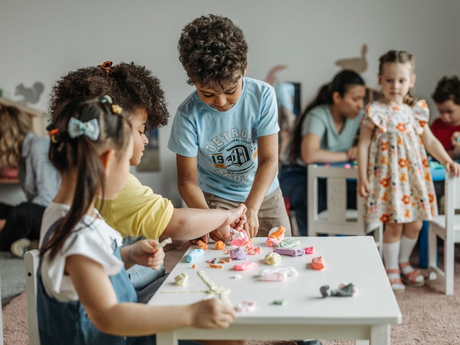 Children playing other at a table doing arts and crafts.