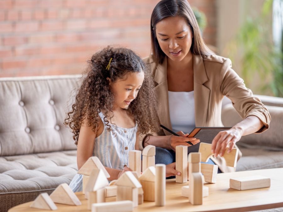 Therapist helping young child build with building blocks.