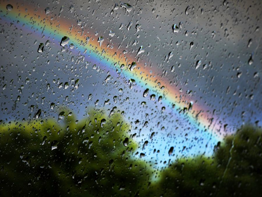 Rain on a window with rainbow in background.