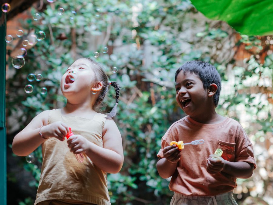 Two children playing with bubbles outside.