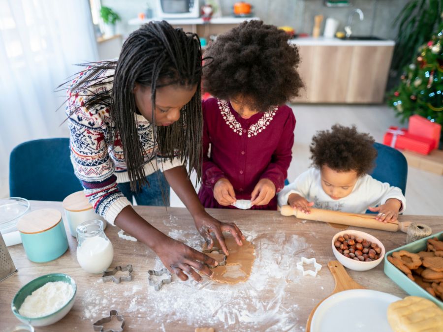 Mother and two children making cookies together.