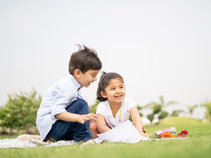 Two young children outside on a blanket.