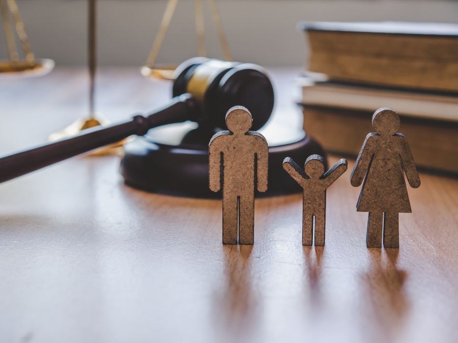 Wood cravings of parents and child next to a gavel.