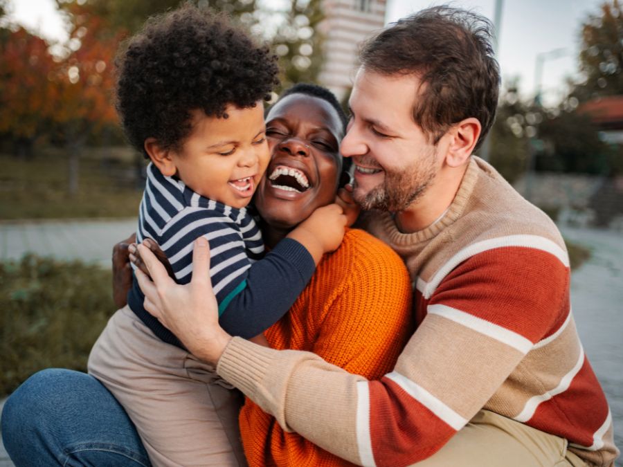 Parents and child hugging and laughing.
