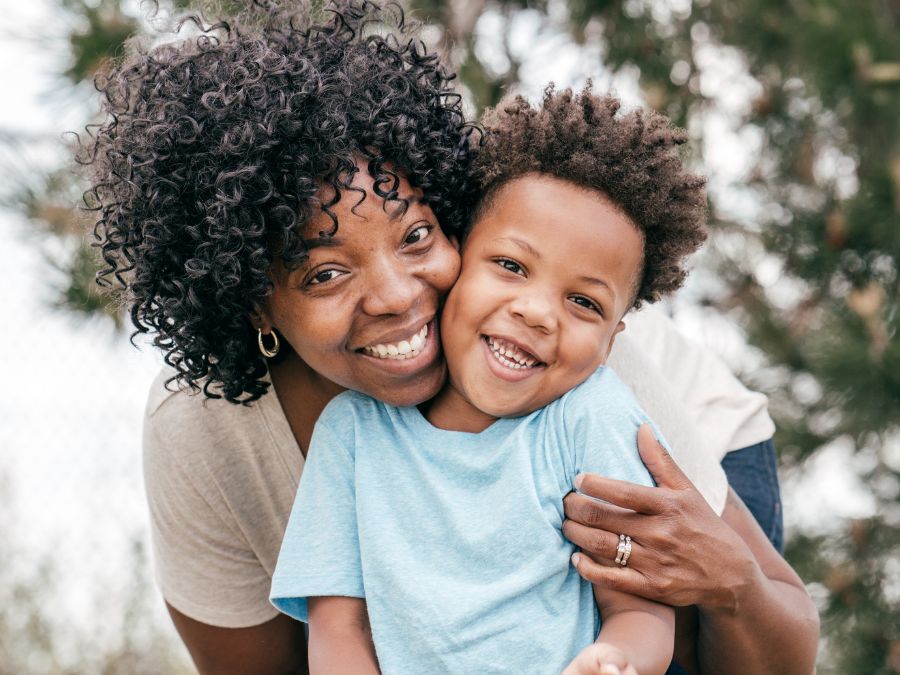 Mother hugging young son outside.