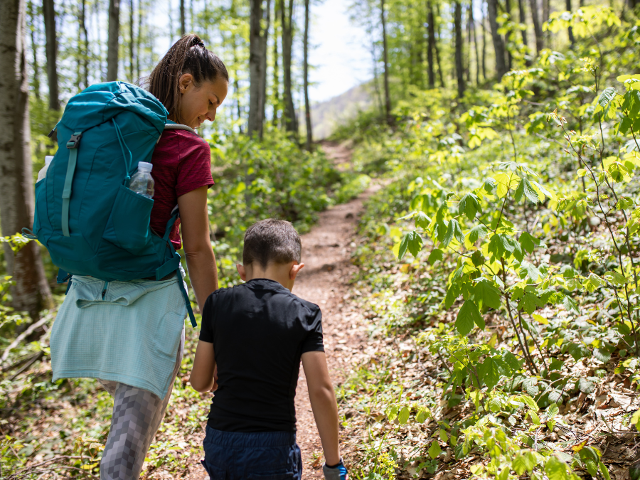Mother and son holding hands hiking in the woods.