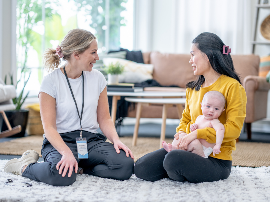 Mother and baby sitting with home visiting staff.
