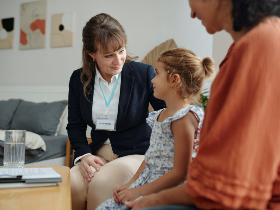 Social worker sitting with mother and daughter in their home.