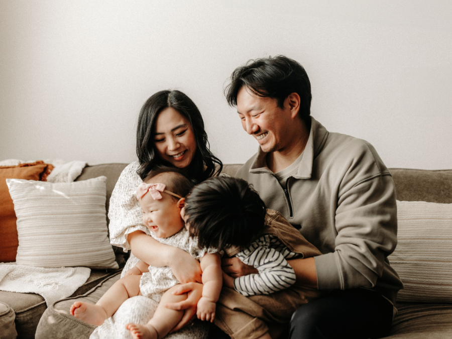 Parents and two young children sitting on a couch together.