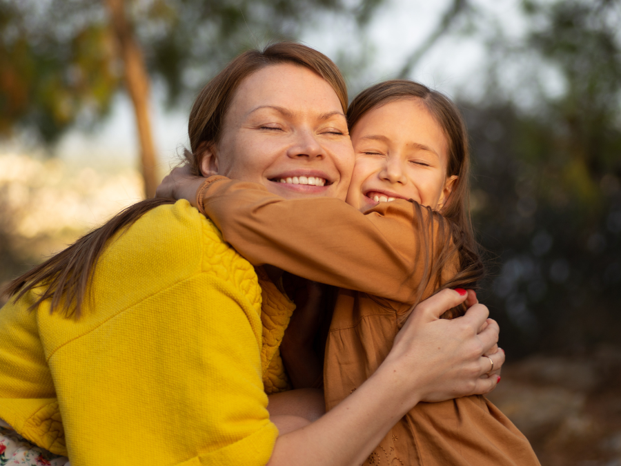 Mother and daughter hugging outside.