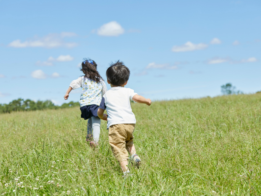 Two children running in tall grass.
